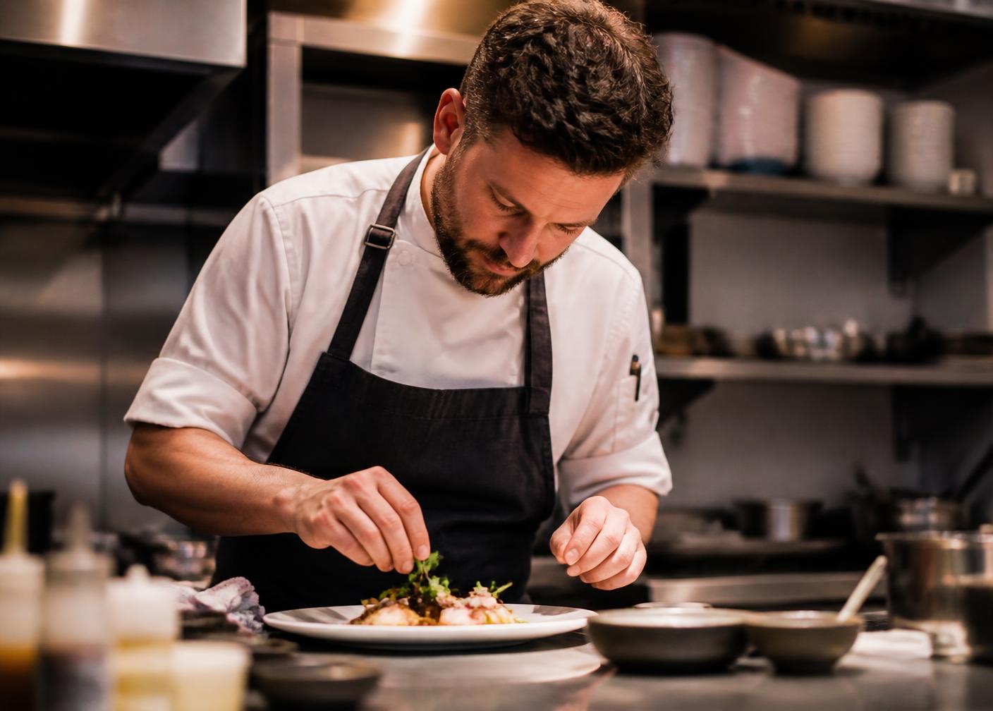 Chef werkt een gerecht af in de keuken van Maison Noord